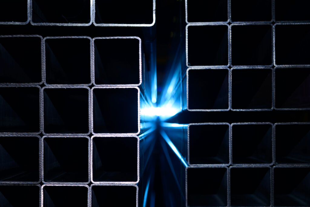 Stos ułożonych kształtowników kwadratowych o metalicznej strukturze z widocznymi krawędziami cięcia